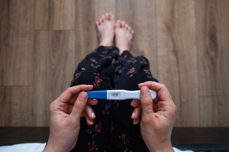 Händer som håller ett positivt graviditetstest.